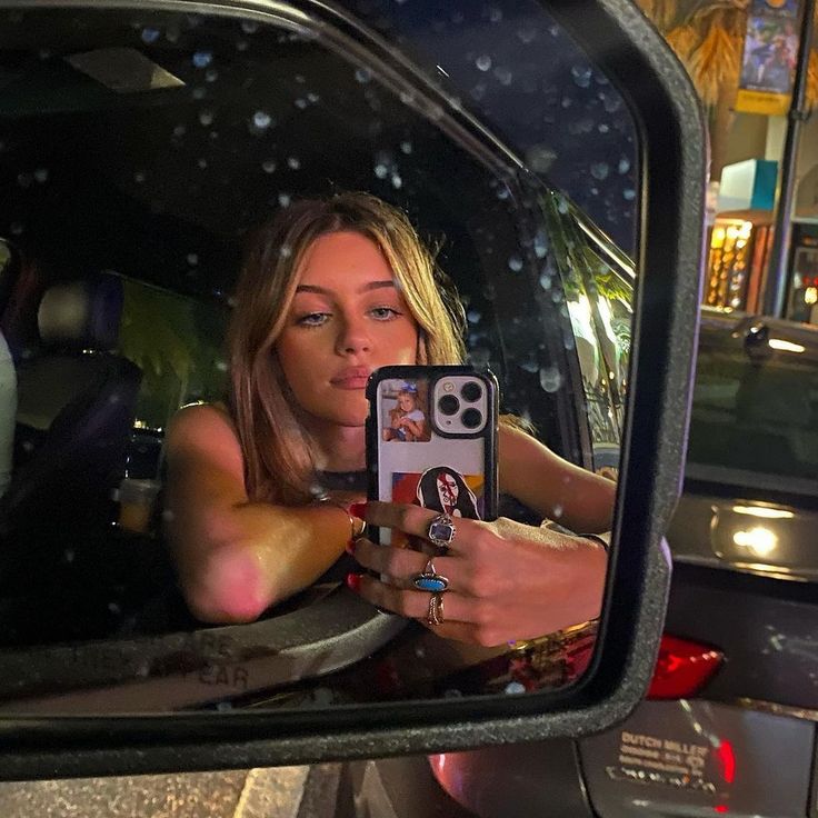 a woman taking a selfie in her car mirror