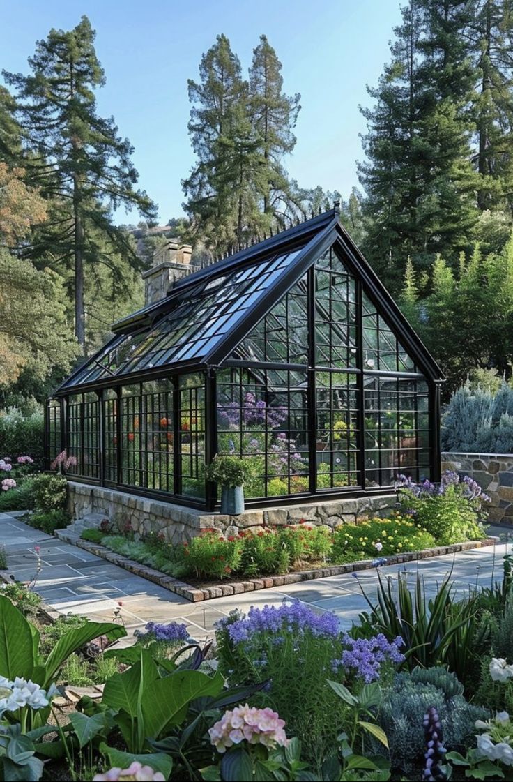 a glass house surrounded by lots of flowers and greenery in the middle of a forest