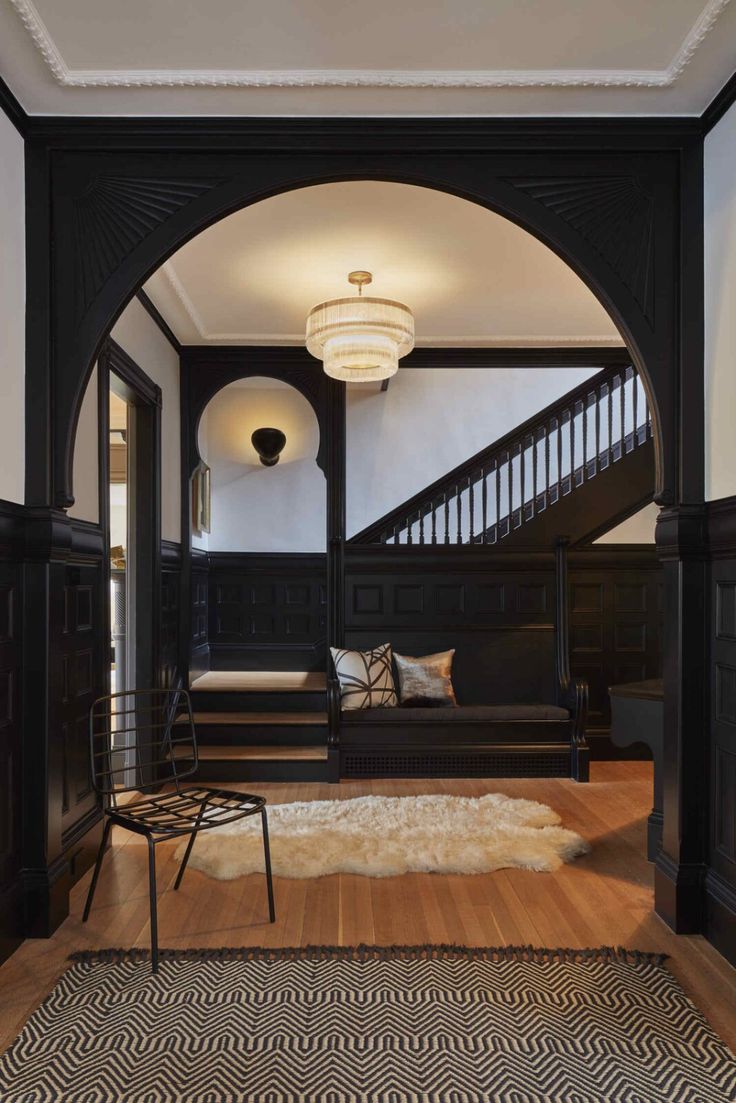 an archway leading to a living room with black furniture and rugs on the floor