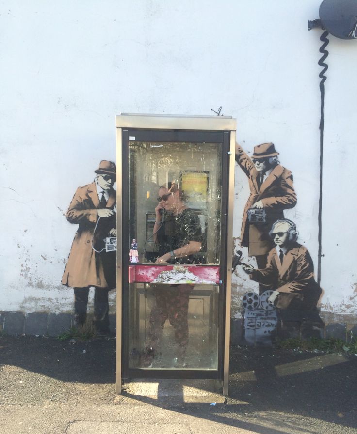 a phone booth painted on the side of a building with two men in coats and hats