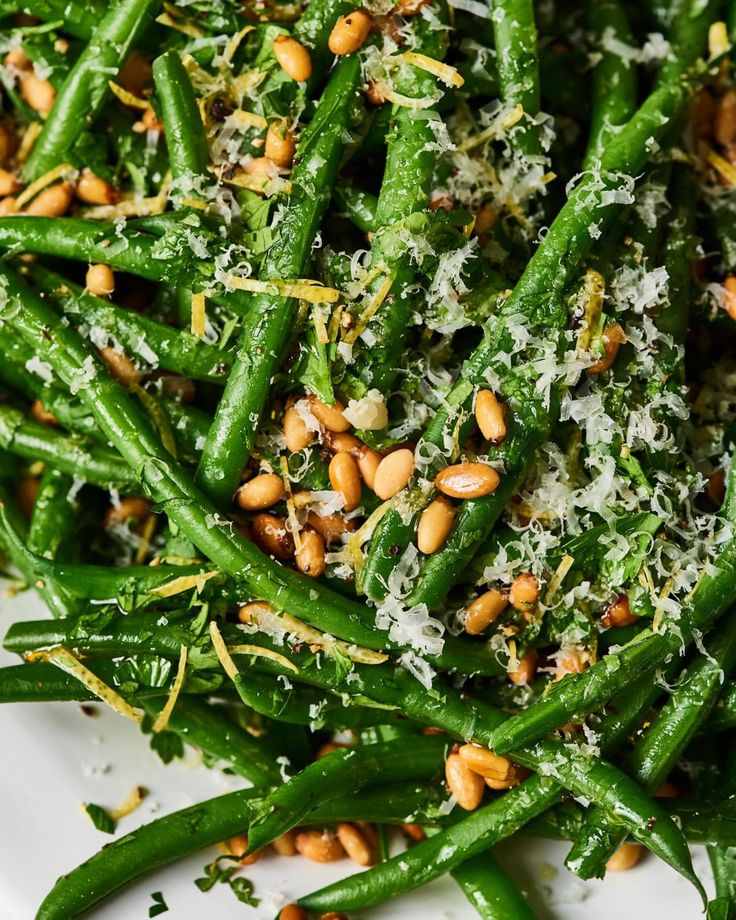 green beans with parmesan cheese and pine nuts on a white plate, ready to be eaten