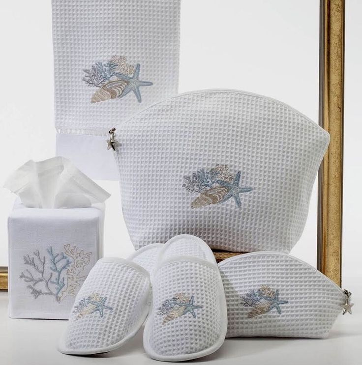 white towels and slippers in front of a gold framed mirror with seashells on them