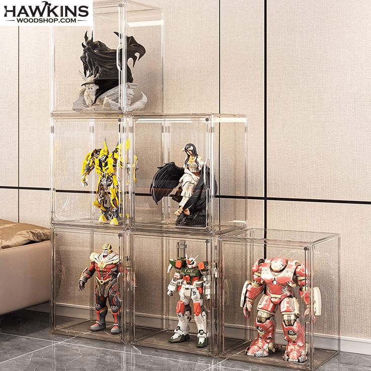 four clear shelves with action figures in them on the floor next to a couch and wall