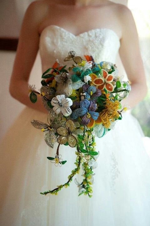 a woman in a wedding dress holding a bridal bouquet with buttons and flowers on it