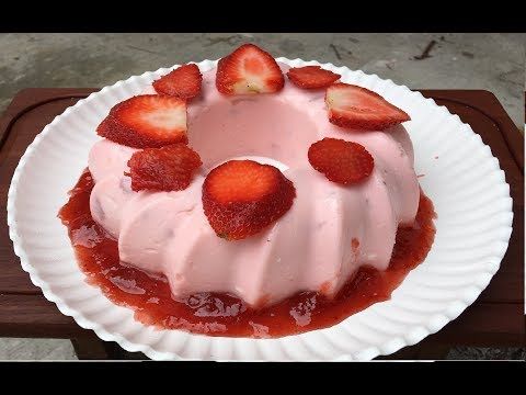 a white plate topped with a cake covered in strawberries on top of a wooden table