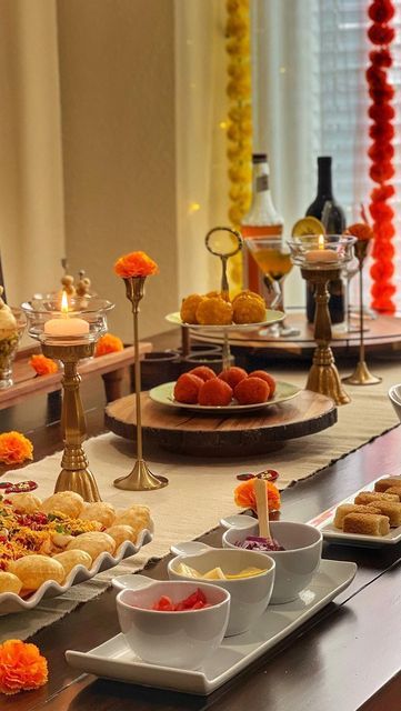 an assortment of food is displayed on a buffet table with candles and flowers in the background