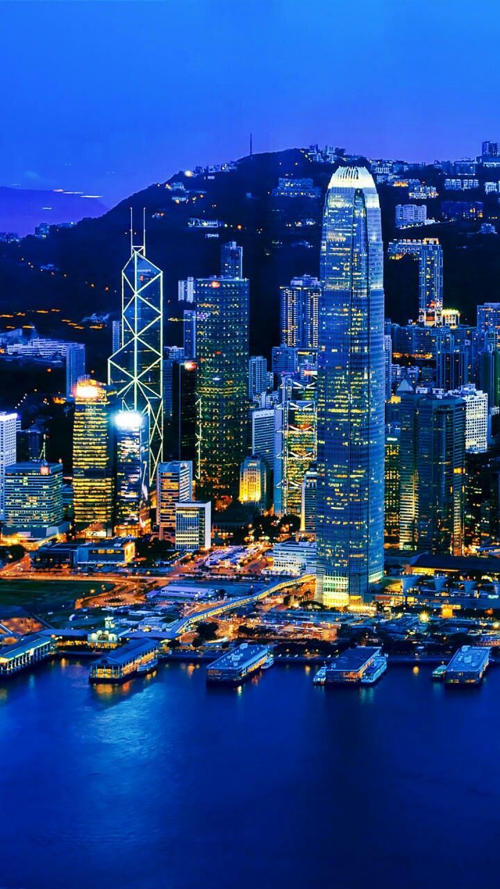 an aerial view of a city at night with boats in the water and skyscrapers lit up