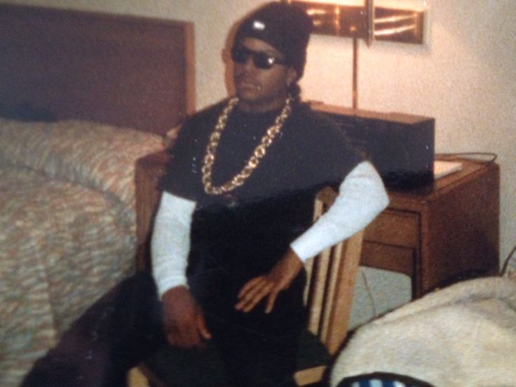 a man sitting on top of a wooden chair next to a bed