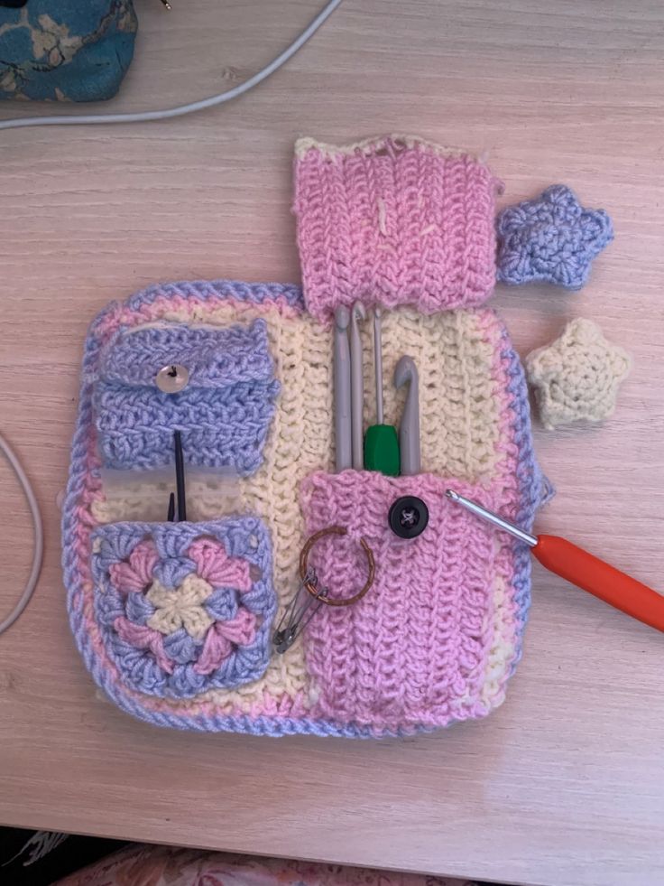 a crocheted purse is sitting on a table next to scissors and other items