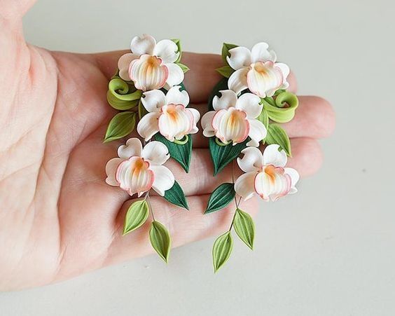 a person holding some flowers in their hand on a white surface with green and pink leaves