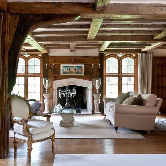 a large living room with wood paneled walls and wooden flooring, along with white rugs