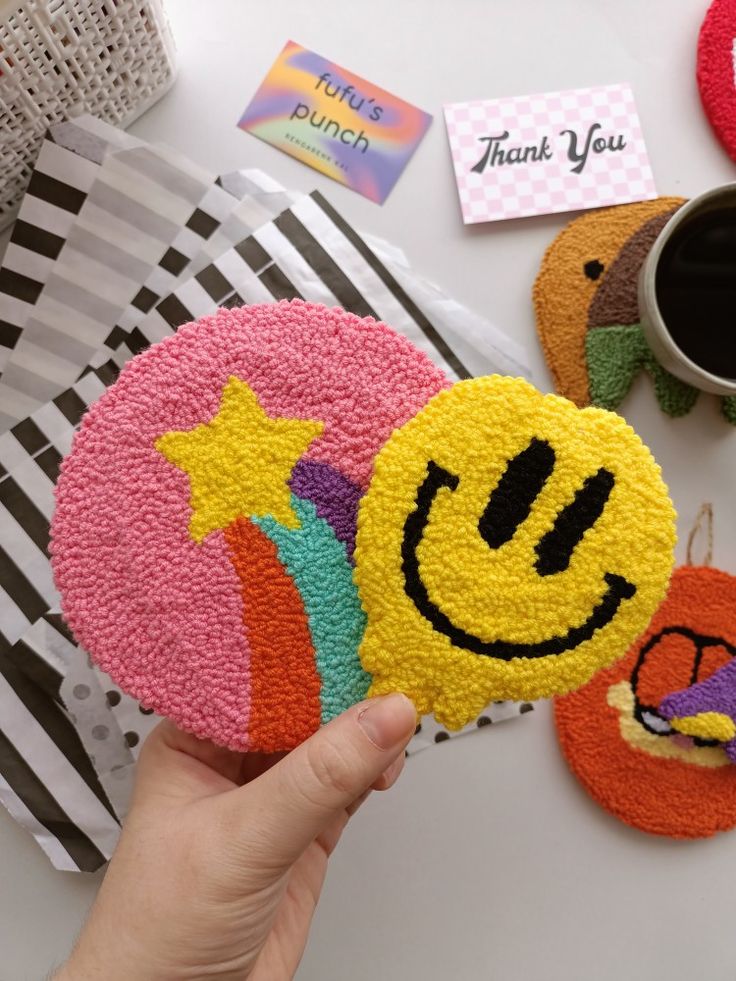 a hand holding a smiley face cake on top of a table next to other decorations