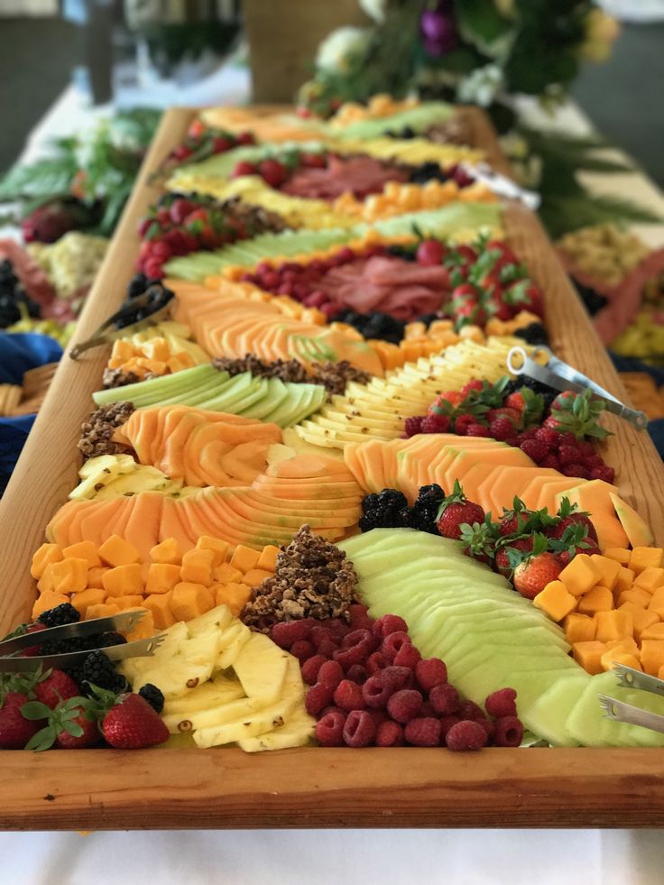 many different types of fruit are arranged on a long table with knifes and forks