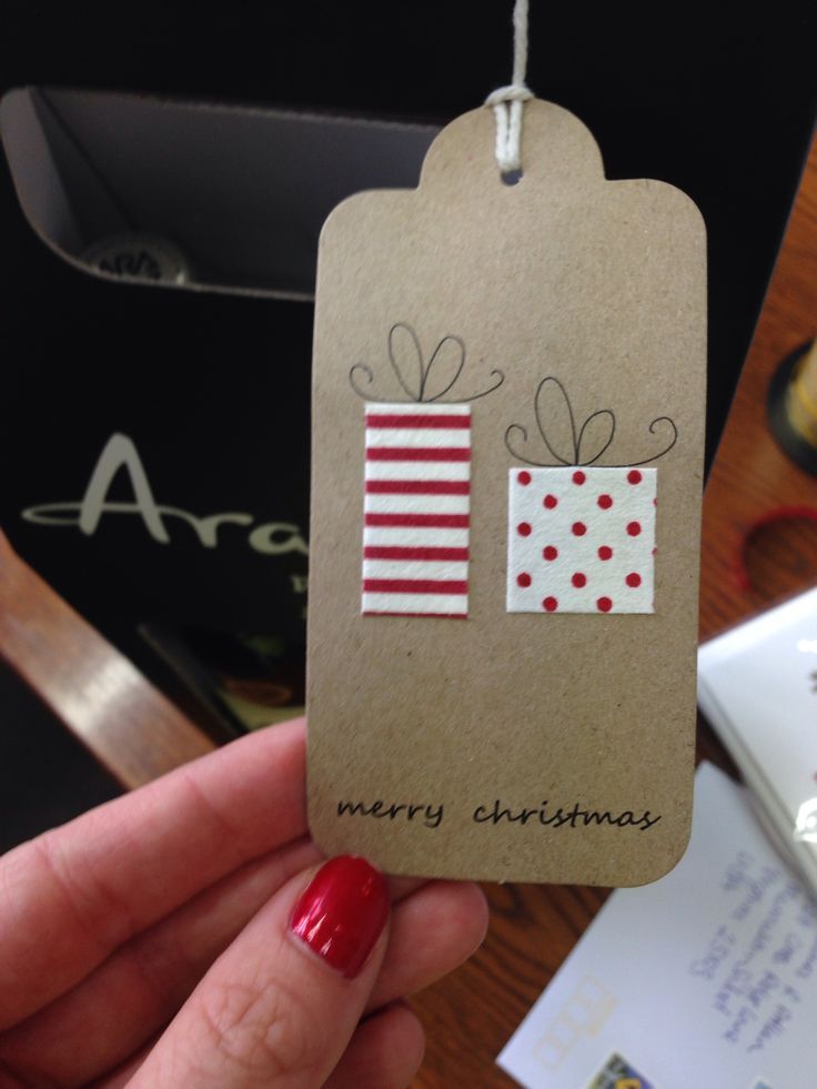 a person holding up a christmas gift tag