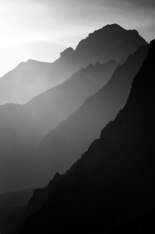 black and white photograph of mountains with fog