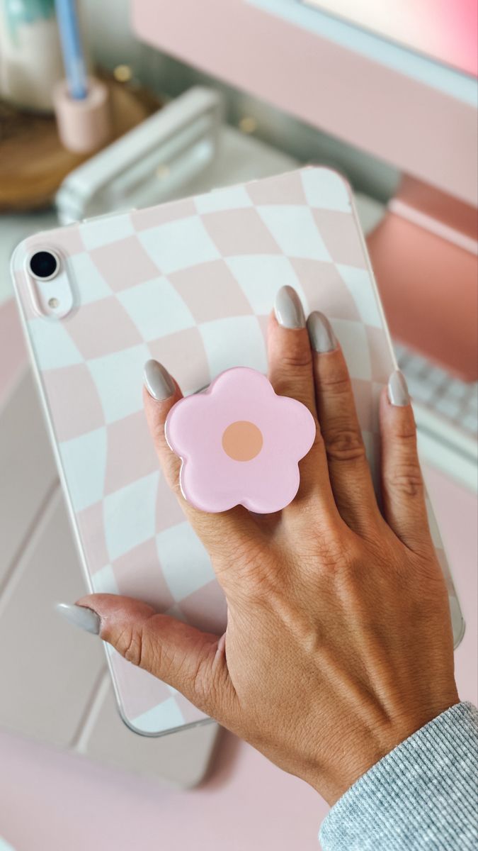 a woman's hand holding an ipad with a pink flower on the front cover