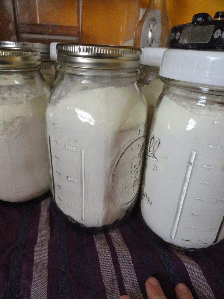 three mason jars sitting on top of a counter next to a person's hand