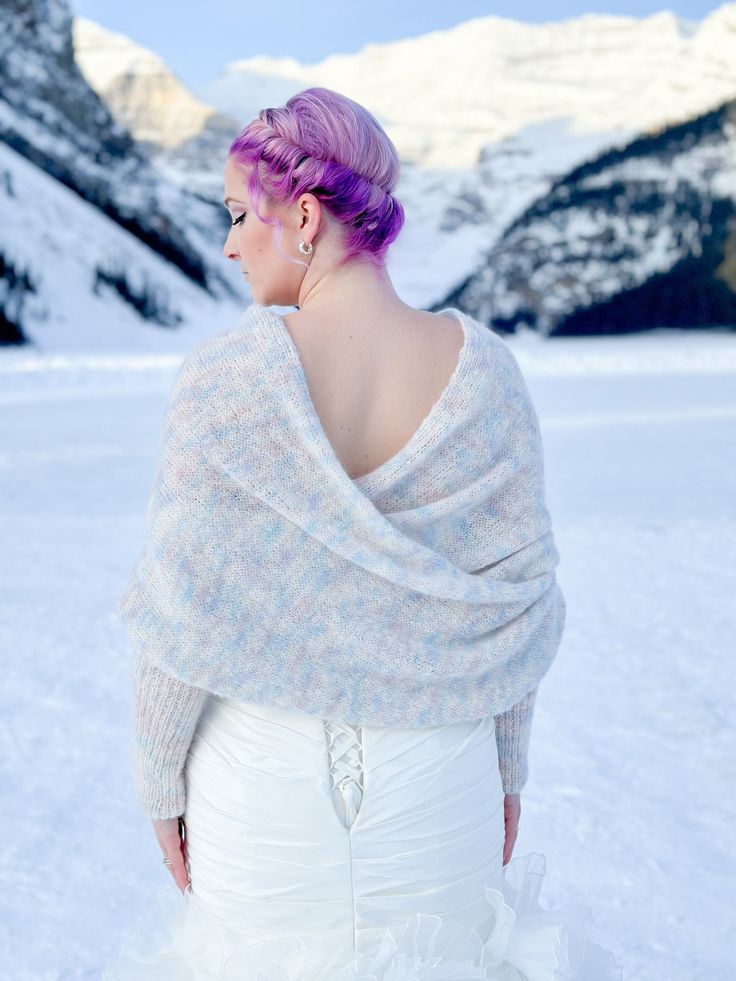 a woman with purple hair is standing in the snow wearing a white dress and shawl