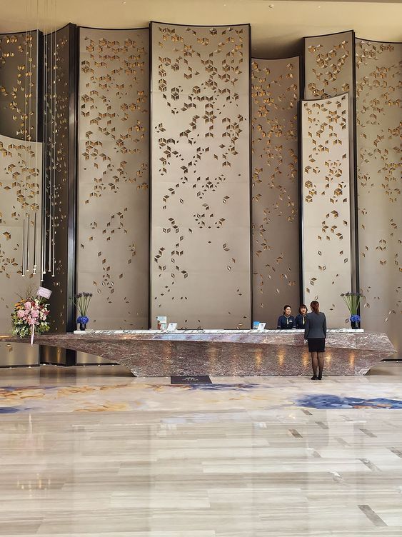 two people sitting at a table in front of some tall wall panels with gold leaves on them