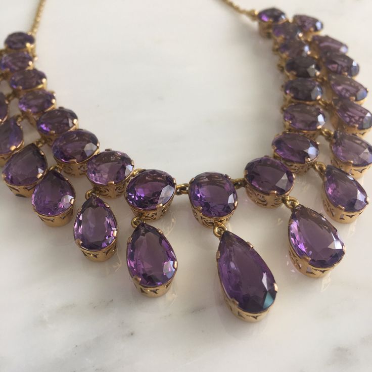 Details: Stunning Amethyst and 14K gold necklace. The necklace along has 34 amethyst ranging in size from 8mm x 9mm to 9.8mm x 17.6mm. The drop on the largest amethyst measures 34.6mm (about 1.4 inches). The appraisal value of this is $5,500. From Appraisal: One (1) fourteen karat yellow gold amethyst fringe necklace. Set in four prong open work gallery crowns are seventeen (17) faceted oval amethysts, graduating out from the center (12.85 x 9.74 x 5.54 mm), weighing approximately 53.77 carats c Opulent Formal Necklaces With 17 Jewels, Elegant Yellow Gold Amethyst Jewelry, Opulent Round Necklaces For Formal Occasions, Elegant Evening Amethyst Jewelry, Elegant Purple Evening Jewelry, Elegant Purple Jewelry For Evening, Elegant Purple Amethyst Necklace, Formal Purple Gemstone Necklace, Elegant Amethyst Jewelry