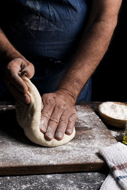 a person kneading dough on top of a wooden table