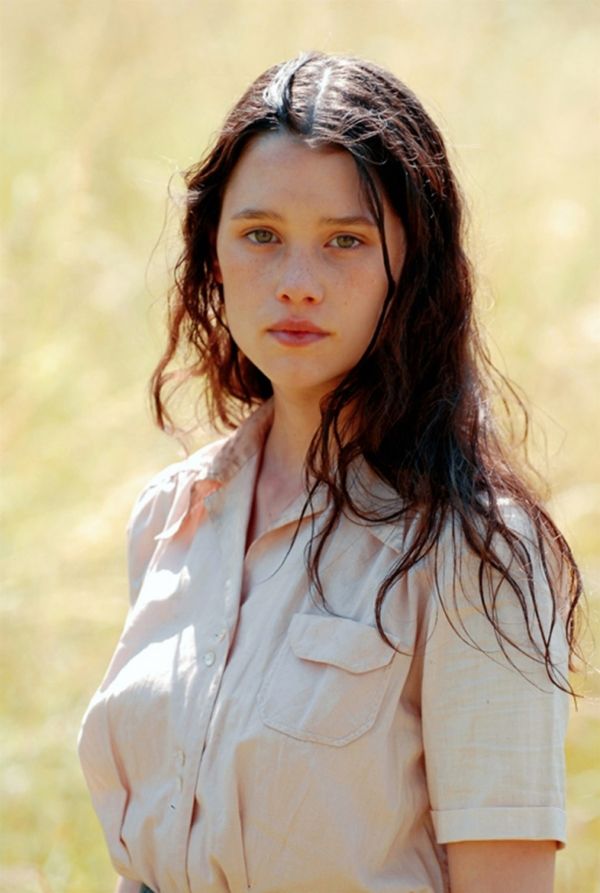 a woman with long hair standing in the grass