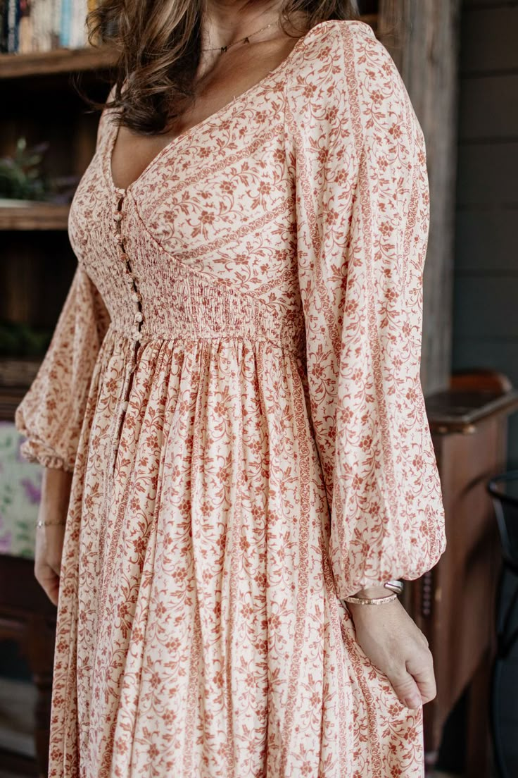 Online exclusive! Get country chic with our Center Button Down Lined Long Sleeve Peasant Floral Peach Dress. The light peach floral print adds playful flair, while the relaxed fit and center button detail let you get in touch with the country life. (Country music not included.) Fit: Relaxed Fit - True to size Model Regan is wearing a size small. Long sleeve Center button down Lined Color: Light Peach Fabric: 100% Rayon / 100% Rayon Lining Brand: In Loom Have questions or need help deciding on fi Modest Cotton Dresses, House Wife Outfits, Homestead Fashion, Floral Peach Dress, Bloom Chic, Front Button Dress, Traditional Femininity, French Style Fashion, Western Chic Fashion