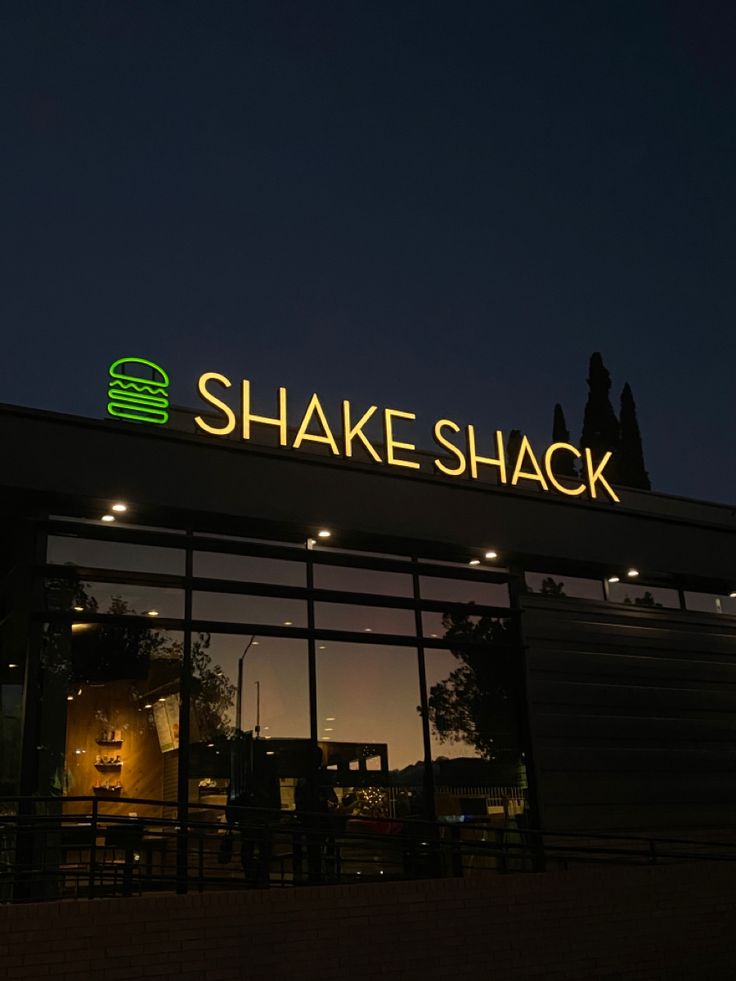 the entrance to shake shack lit up at night