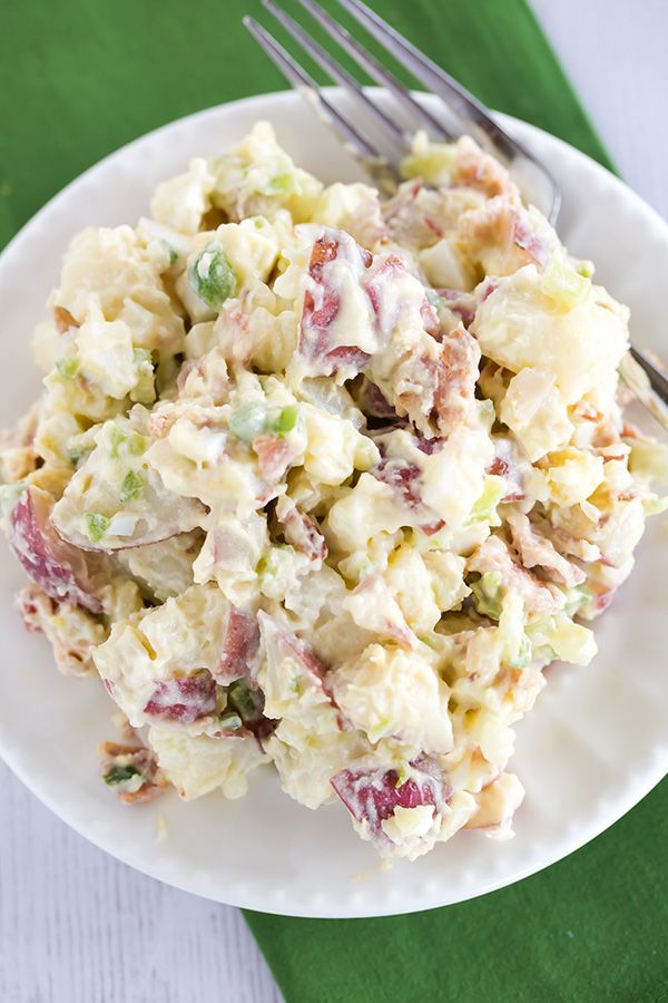 a white plate topped with potato salad next to a fork