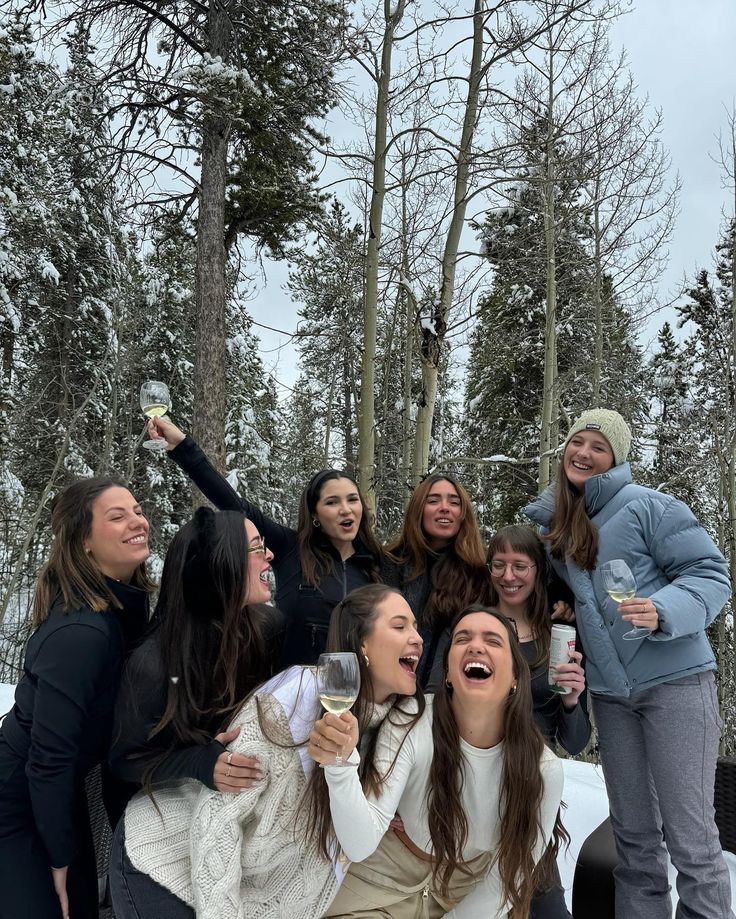 a group of young women standing next to each other in front of snow covered trees