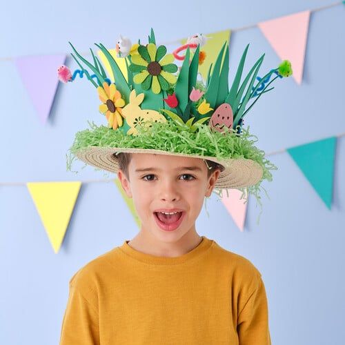 a young boy wearing a straw hat with flowers and grass on it's head