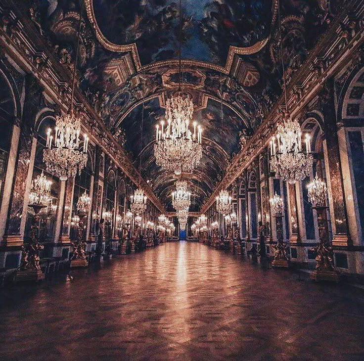 an ornate hall with chandeliers and paintings on the ceiling is lit by lights