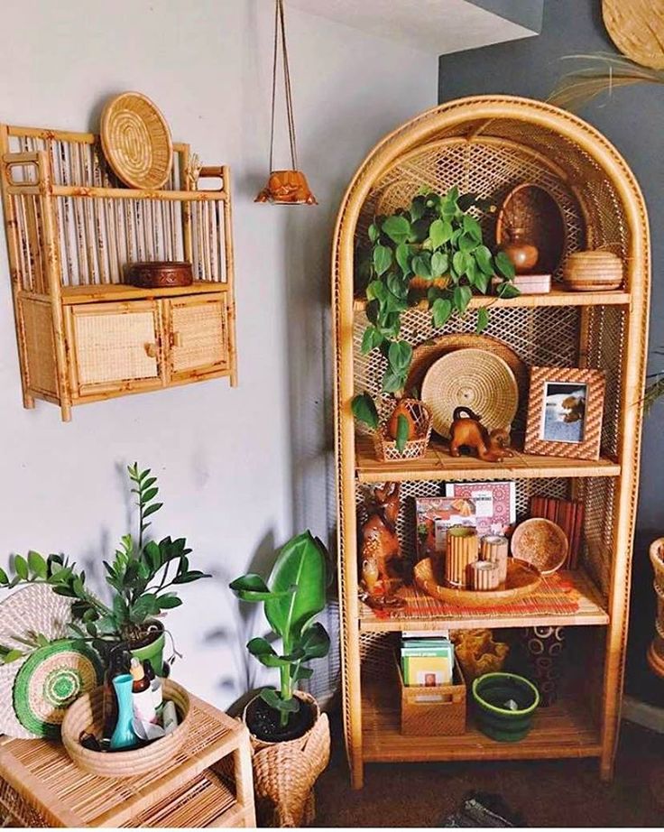 a wicker shelf with plants and pictures on it in the corner of a room