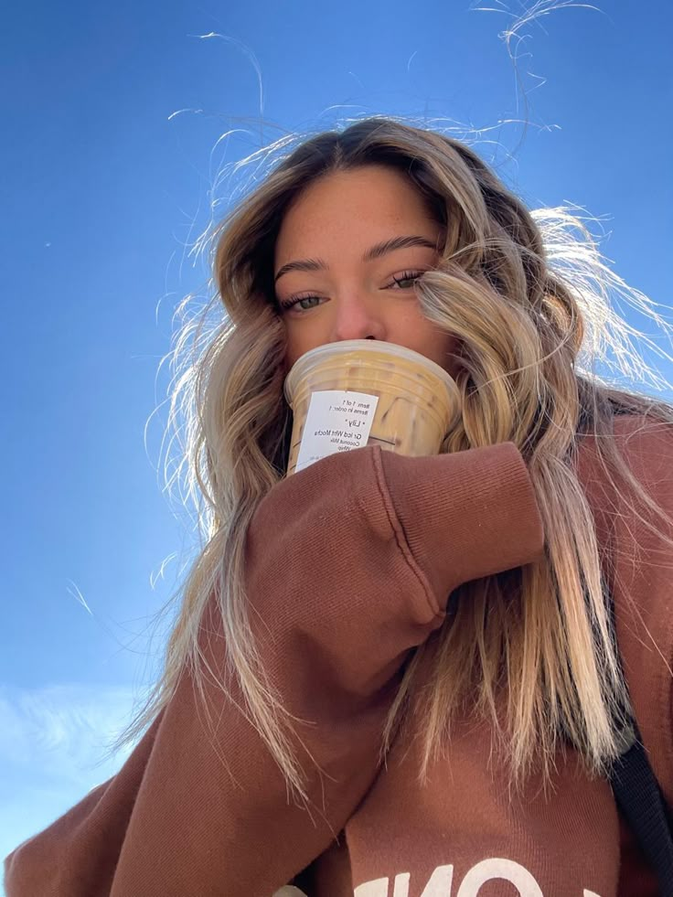 a woman with blonde hair drinking from a coffee cup