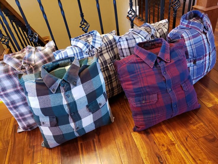 three plaid shirts sitting on the floor next to a stair case and hand rail, all in different colors