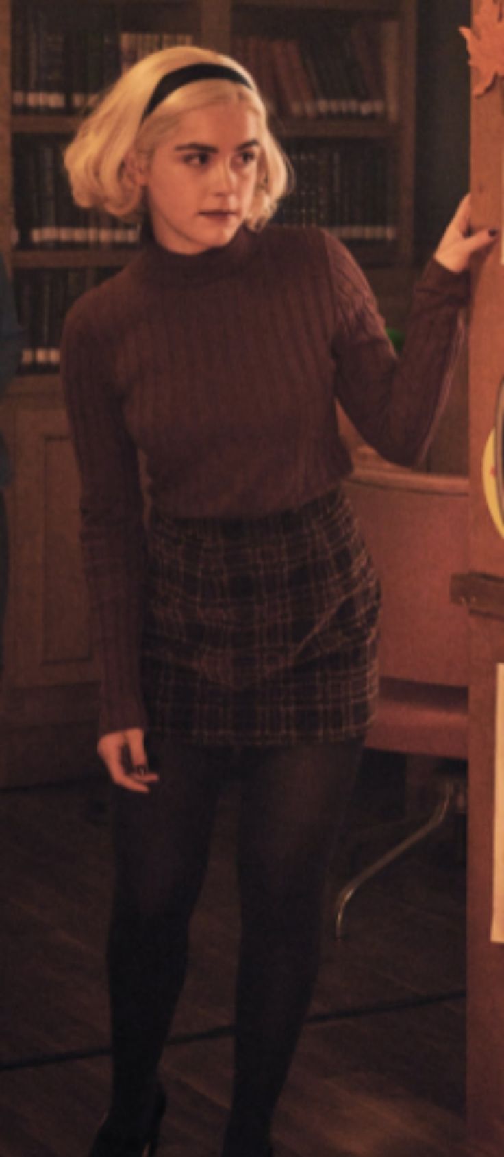 a woman in tights and heels standing next to a book shelf with a clock on it