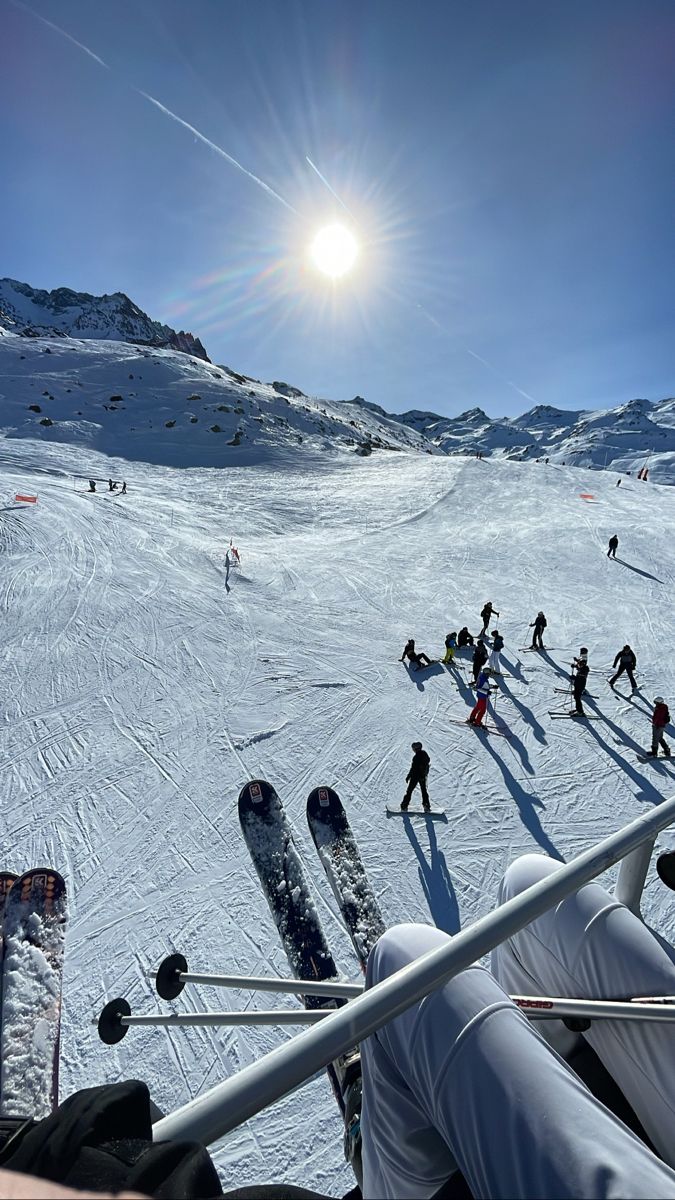 skiers and snowboarders in the sun on a snowy mountain slope, viewed from above