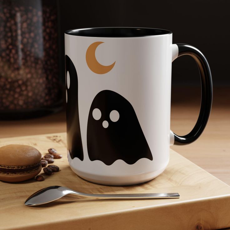 a white and black coffee mug sitting on top of a cutting board next to a spoon