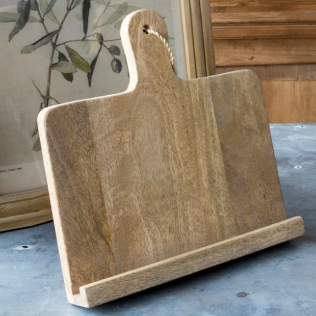 a wooden cutting board sitting on top of a table next to a framed photo and vase