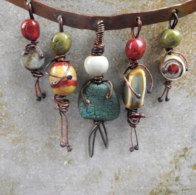 a group of different colored beads hanging from a metal hook on top of a stone wall