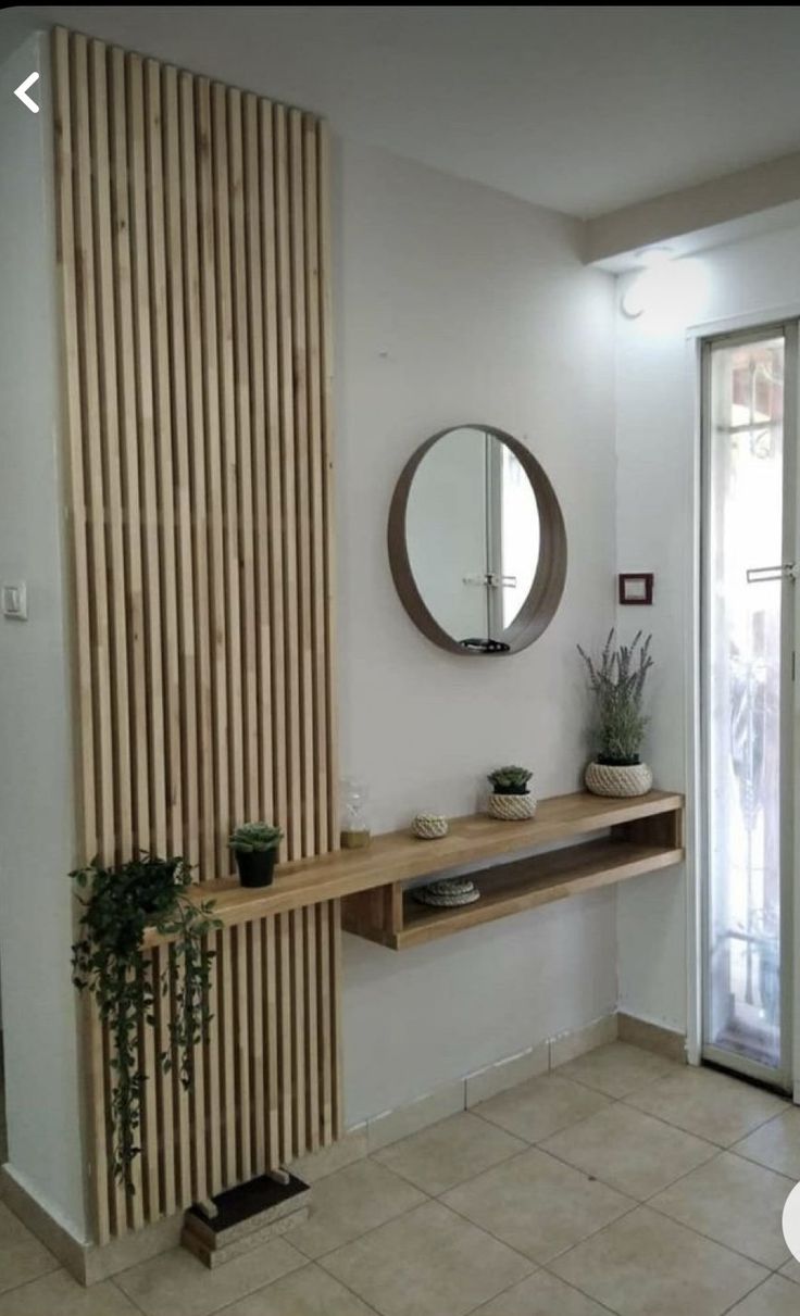 there is a mirror on the wall and a shelf with plants in front of it