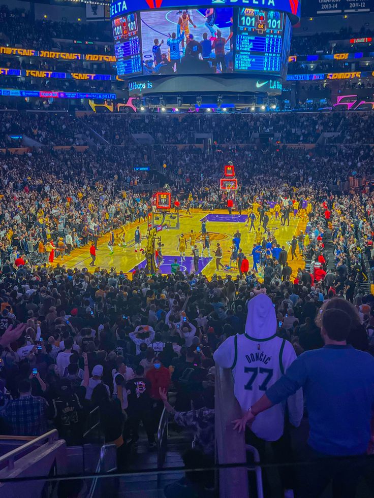 a basketball game is being played in an arena with people watching from the sidelines