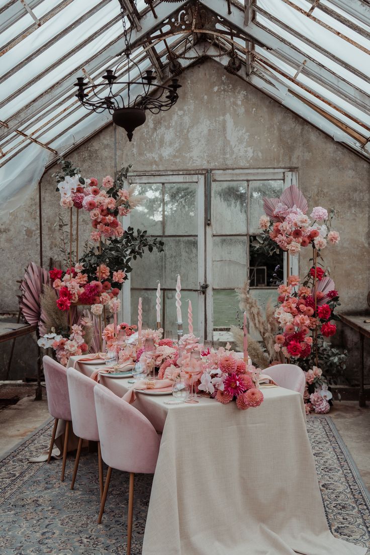 a dining room table with pink chairs and flowers on the tables in front of it