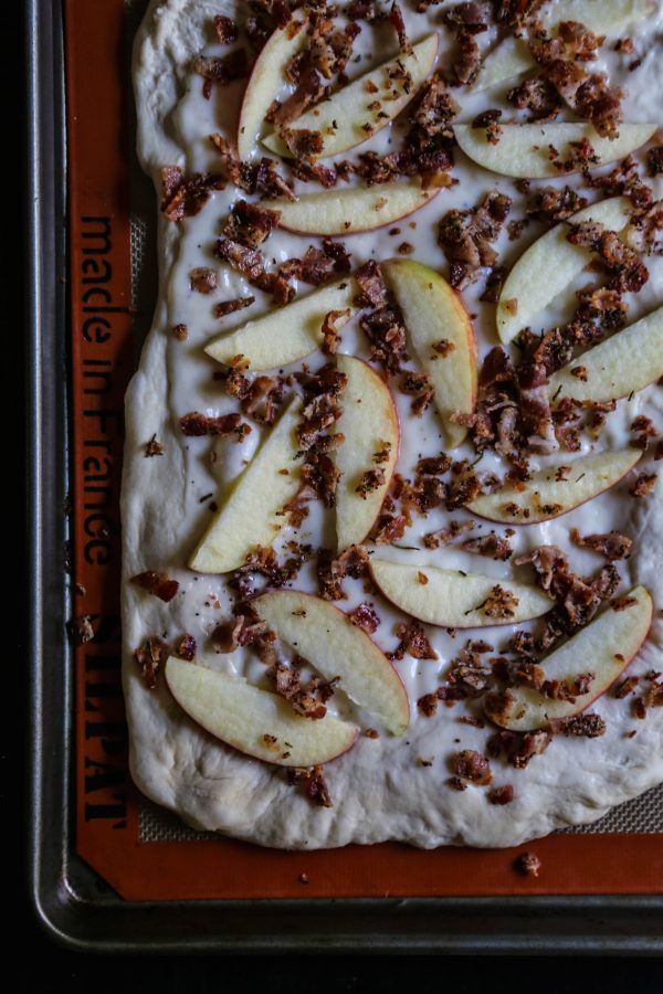 an uncooked pizza topped with apples and nuts on top of a baking sheet