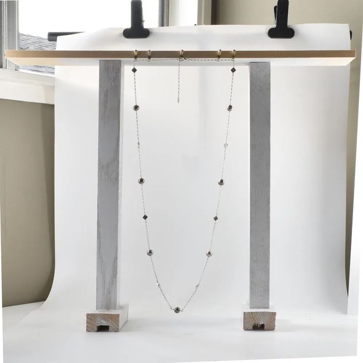 a white backdrop with two necklaces hanging from it's sides