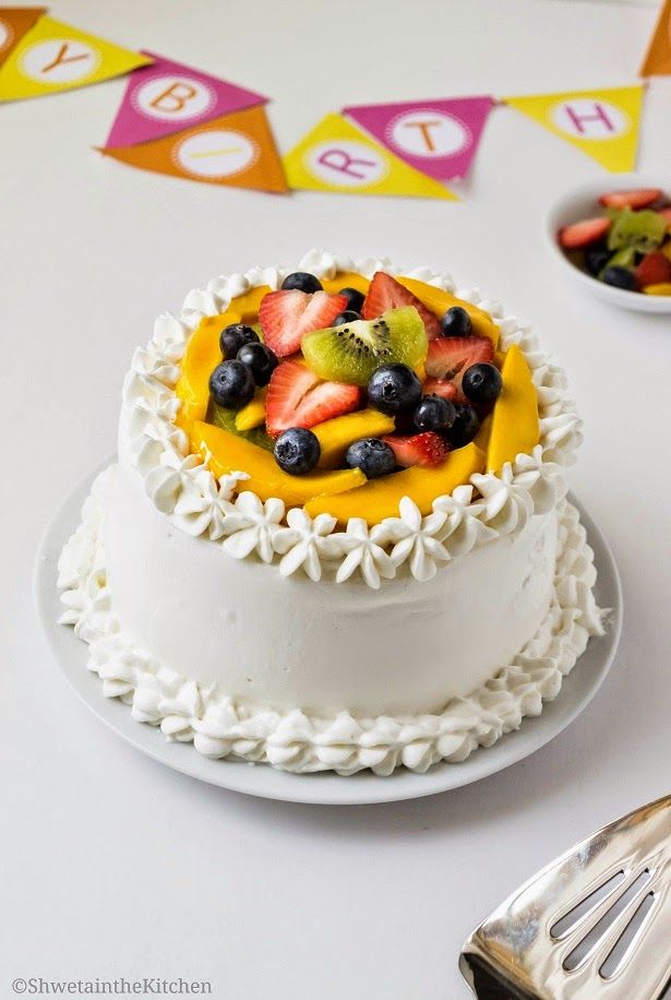 a white cake topped with fruit on top of a table