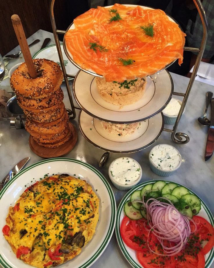 three plates with different types of food on top of each plate, along with bread and vegetables