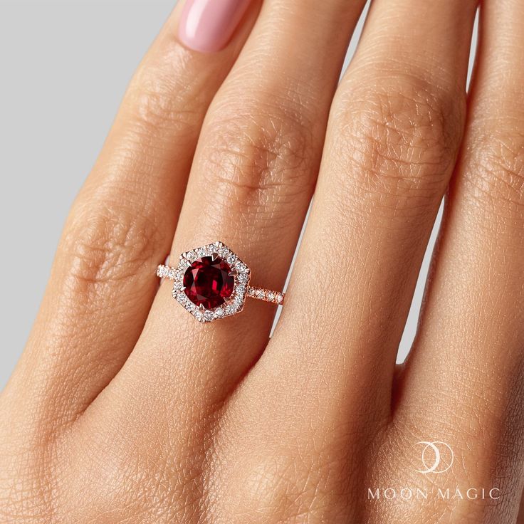 a woman's hand with a ring on it and a red stone in the middle