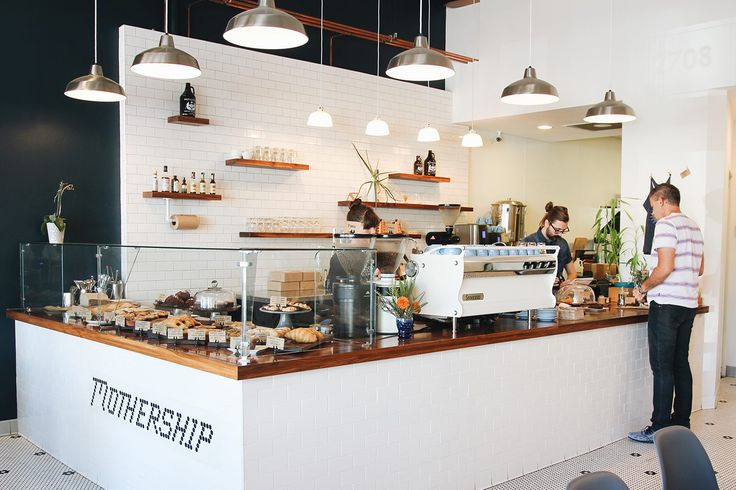 two people standing in front of a counter with food on it and hanging from the ceiling