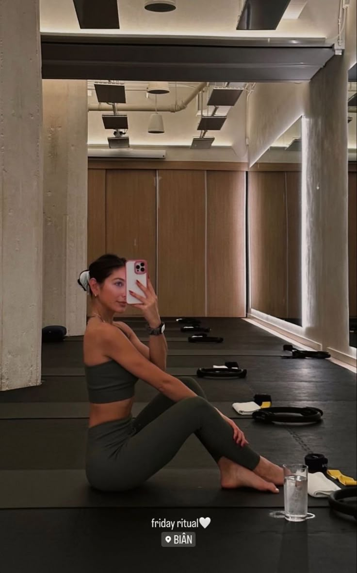 a woman sitting on the floor taking a selfie with her cell phone in an empty room